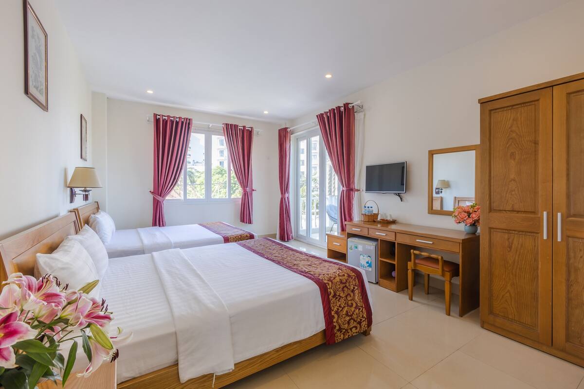 A hotel room with two beds, a desk, a TV, and a wardrobe.