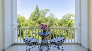 A balcony with white railings, a round table with a vase of flowers, and two chairs. - T&T Resort And Spa (Phu Quoc)