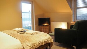 Habitación de hotel con cama, televisión, silla y ventana con vistas.