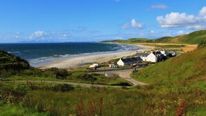 Un pueblo costero con una playa de arena, casas y una vista despejada del mar.