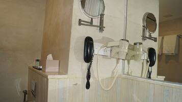 A bathroom with a mirror, a hairdryer, a telephone, and a tissue box.