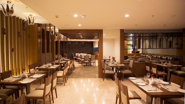 Un restaurante moderno con varias zonas de comedor, paneles de madera y un espacio central abierto.