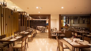 A modern restaurant with multiple dining areas, wooden paneling, and a central open space.