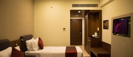 Habitación de hotel con dos camas, televisor, escritorio y puerta al baño.