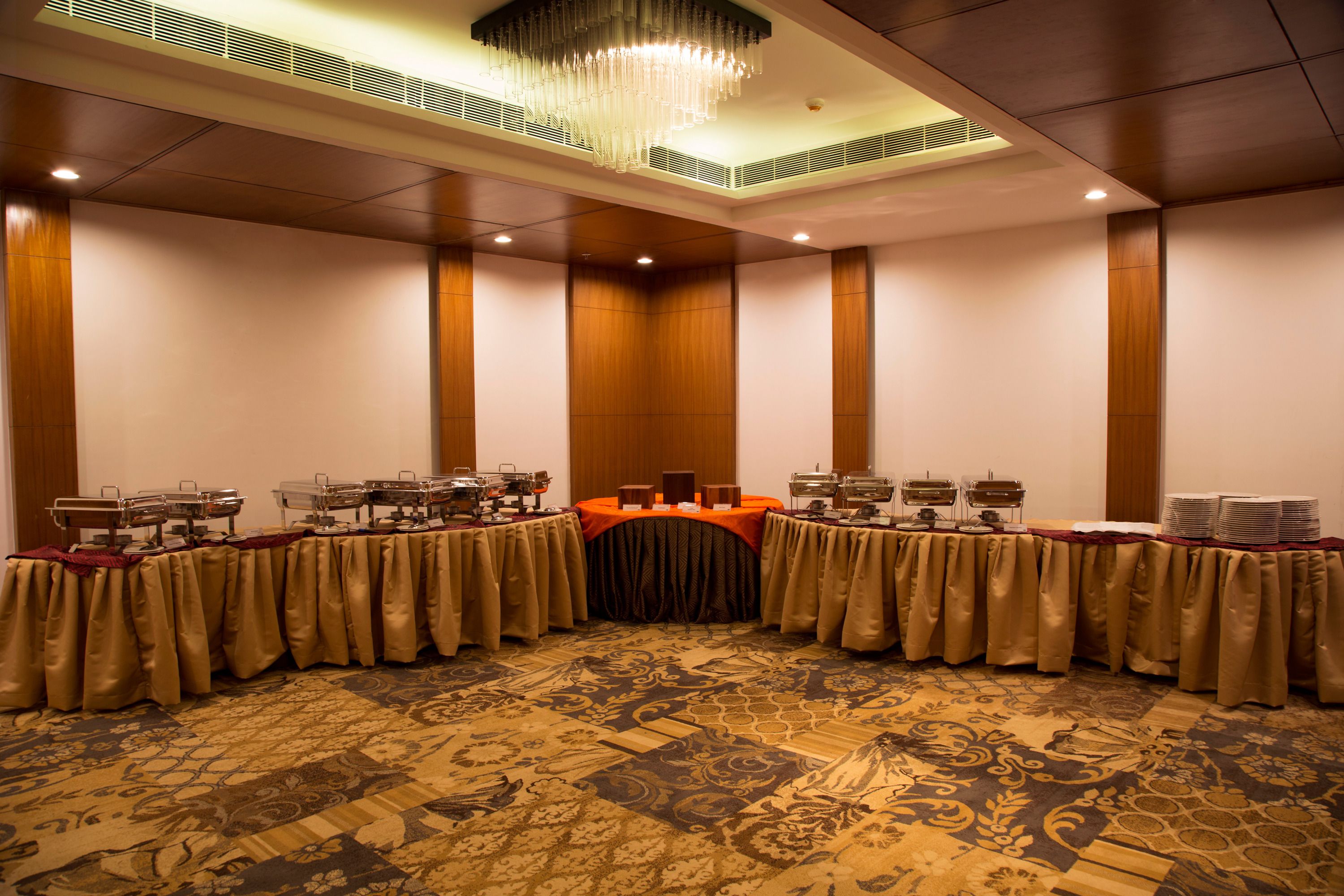 A conference room with a long table, multiple serving stations, and a chandelier.