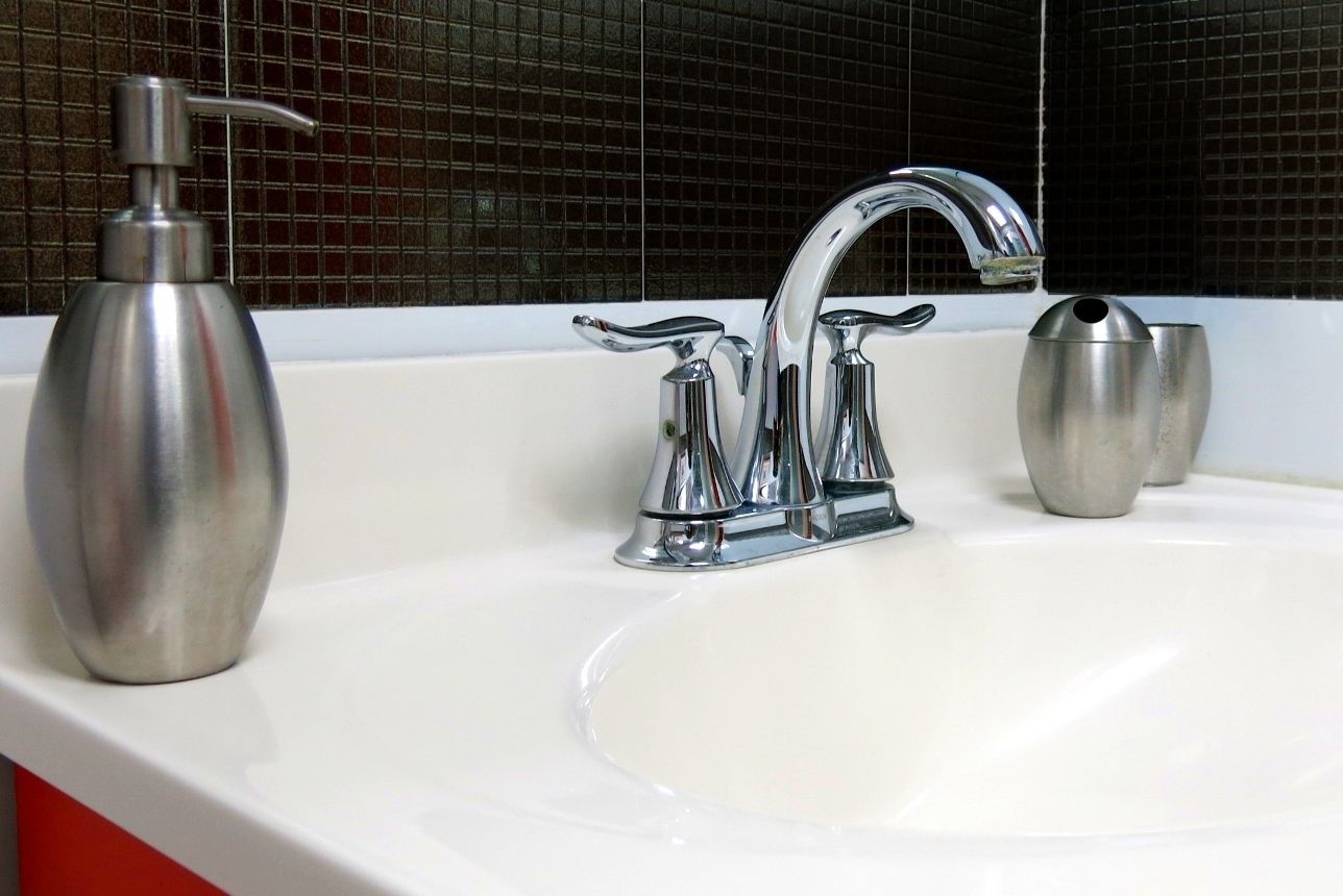 A bathroom sink with a chrome faucet and a soap dispenser.