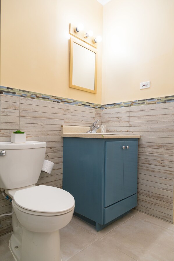 A bathroom with a toilet, sink, and cabinet.