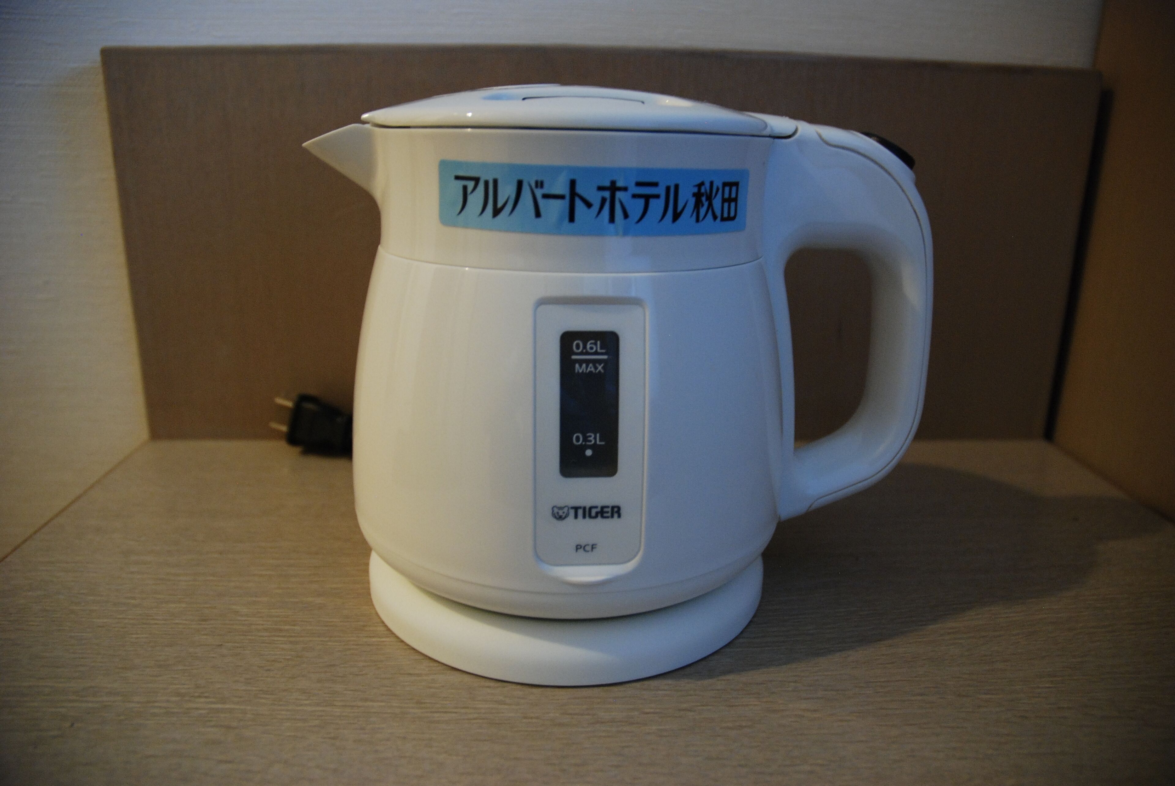 A white electric kettle with a digital display and a label in a foreign language.
