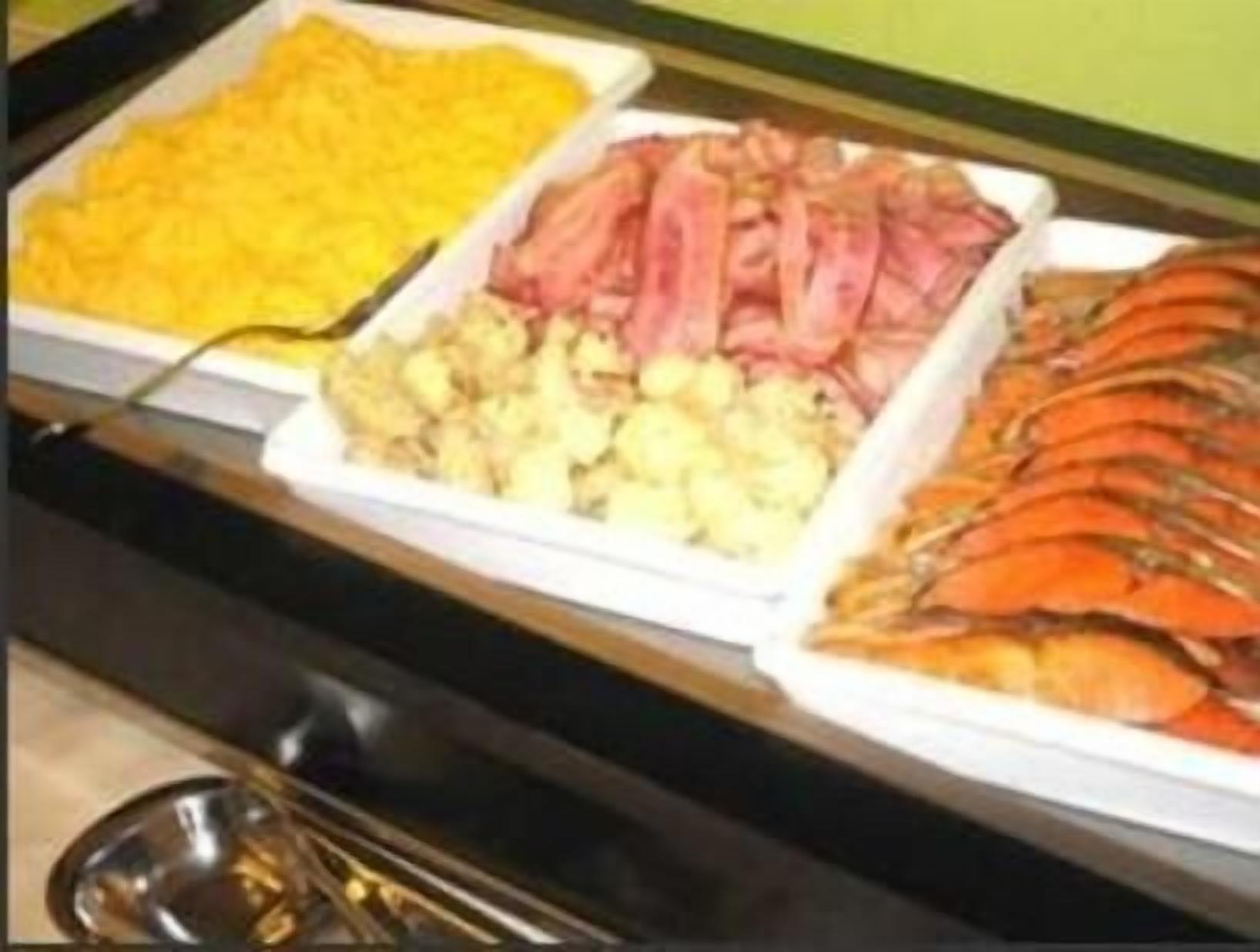 Un buffet proposant une variété de plats, notamment des œufs brouillés, du bacon et des crevettes.