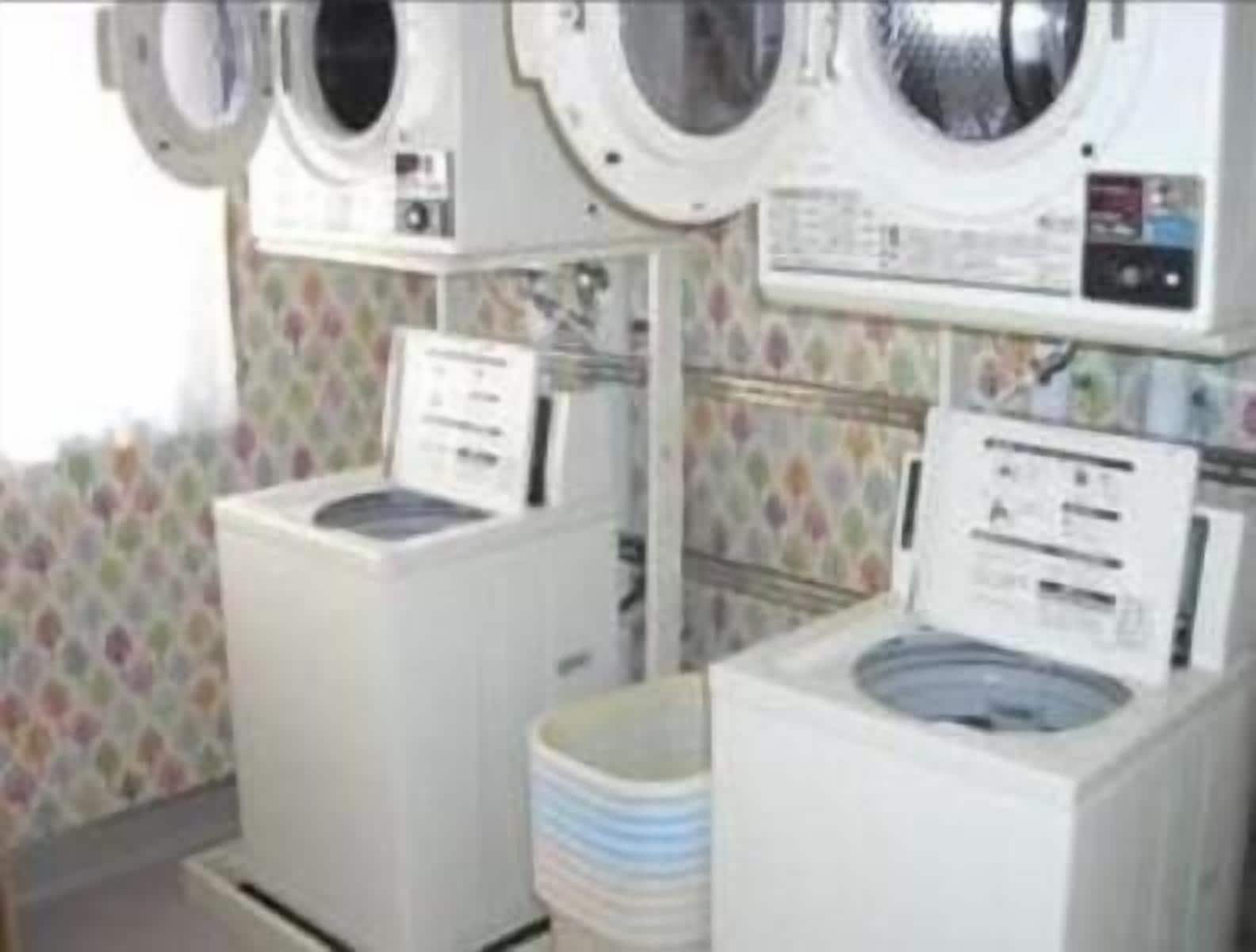 A laundry room with two front-loading washing machines and a stacked washer and dryer.
