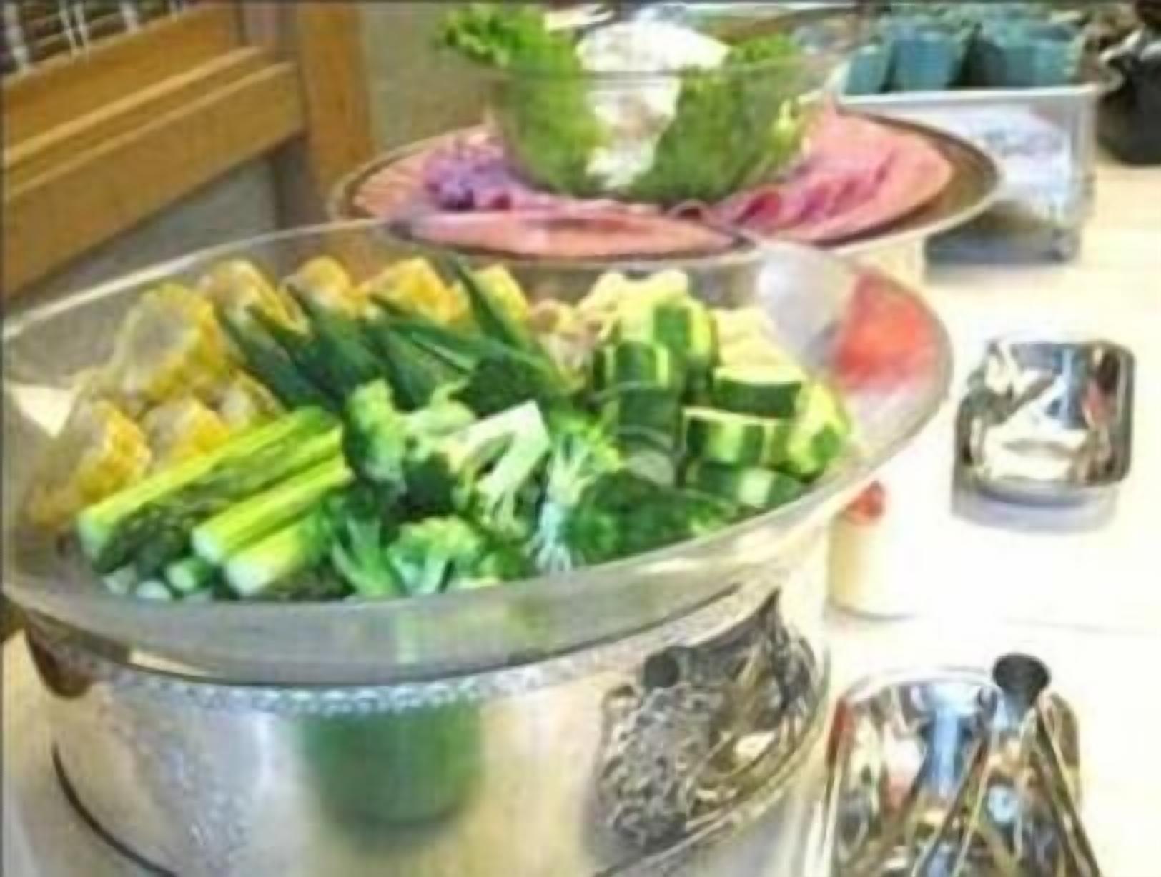 A buffet table with various dishes including vegetables and possibly some meat.