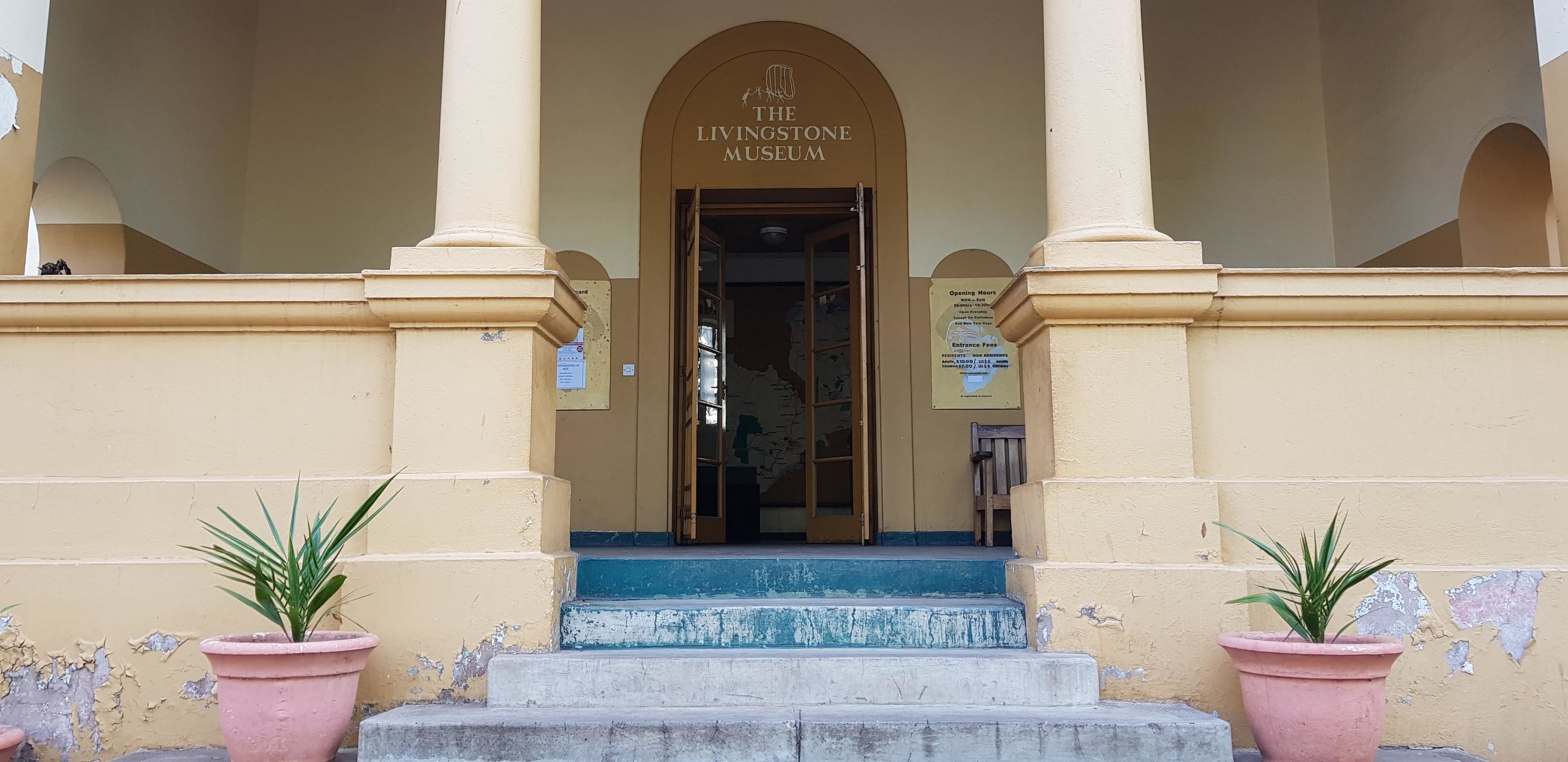 The entrance to The Livingstone Museum with a sign above the door and a bench to the right.