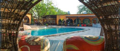 A pool area with wicker furniture and colorful cushions.