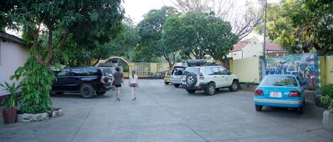 A parking lot with several cars and a few people walking.