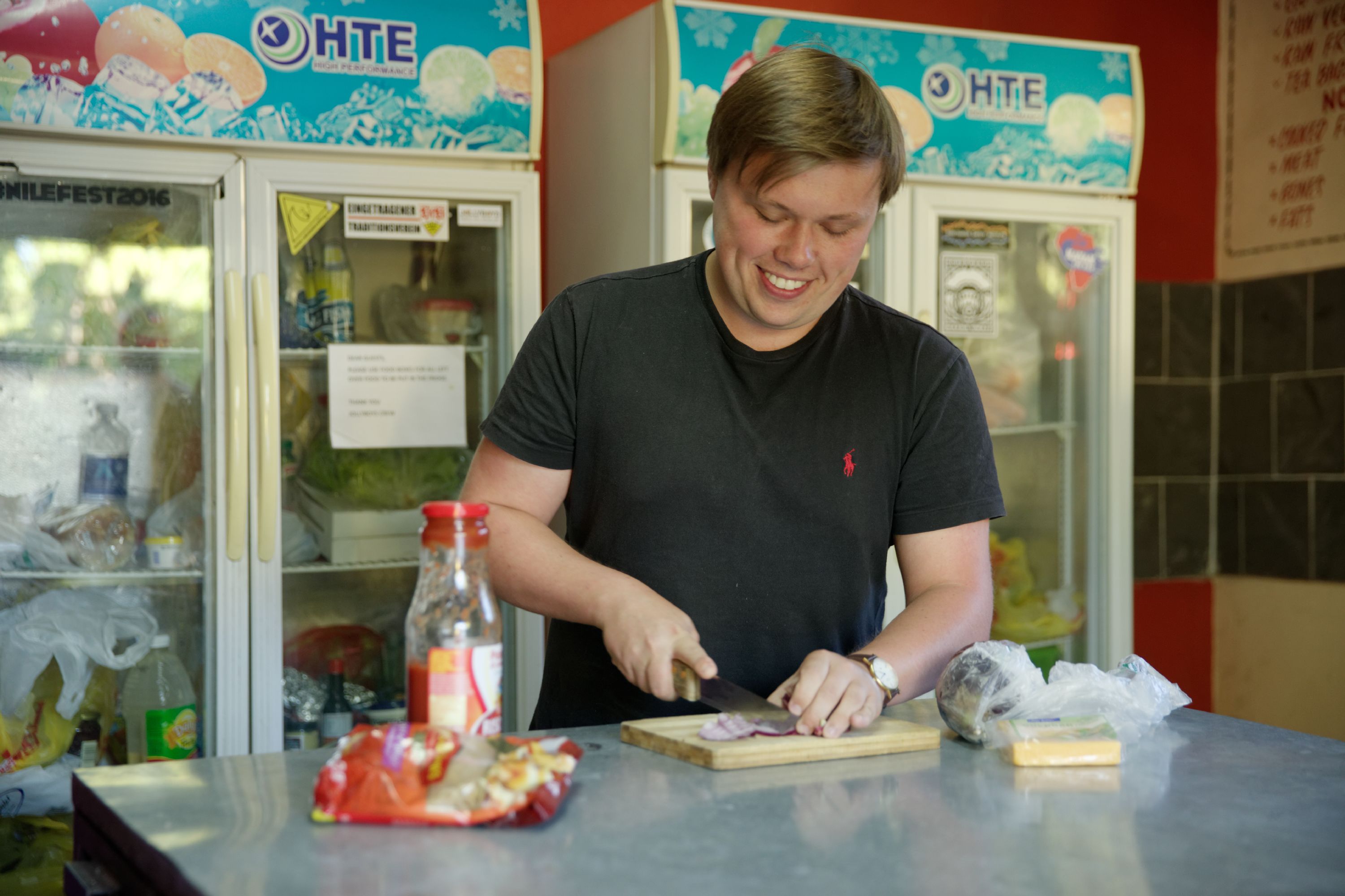 A person cutting vegetables at a counter with a refrigerator in the background.
