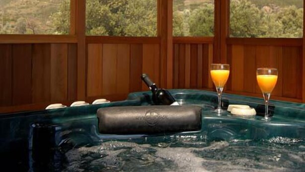 Zona de spa con un jacuzzi, dos vasos de jugo de naranja y una botella de loción.