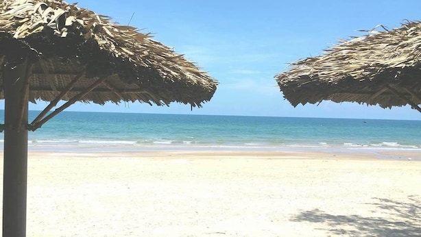 A beach with two thatched umbrellas and a clear view of the ocean. - Suoi Nuoc Resort (Mui Ne)