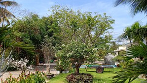 A well-maintained garden with various potted plants, a lawn, and a stone structure. - Suoi Nuoc Resort (Mui Ne)