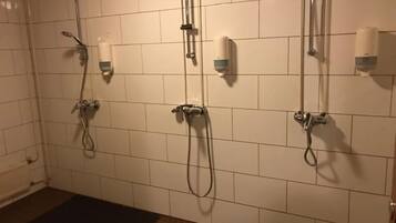 Zona de ducha con múltiples cabezales de ducha y secadores de manos en la pared.