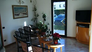 A dining area with a table, chairs, a potted plant, and a television. - Residence Vezzoli (Darfo Boario Terme)