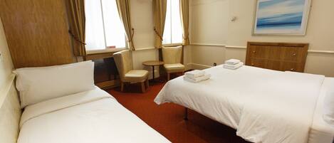 A hotel room with two beds, a TV, a small table, and a chair.