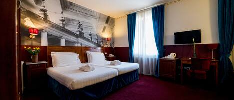 Habitación de hotel con una cama grande, un escritorio, una silla, un televisor y un ventilador de techo.