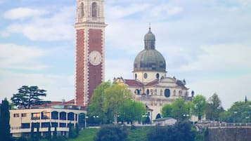Un edificio histórico con una torre de reloj y una cúpula, rodeado de exuberante vegetación y un cielo despejado.