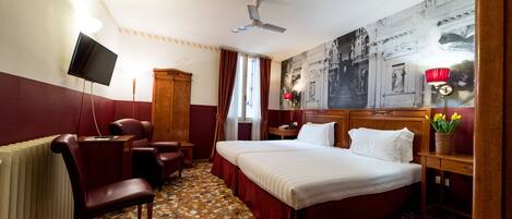 A hotel room with a bed, a desk, a chair, a television, and a large painting on the wall.