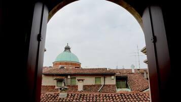 A view through an archway of a building with a dome and terracotta roof tiles.