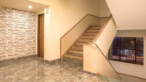 Ein modernes Interieur mit Marmorboden, einer Treppe mit Holzdielen und einer strukturierten Wand.