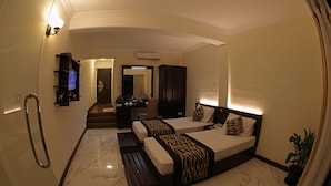 A hotel room with two beds, a desk, a mirror, and a bathroom.
