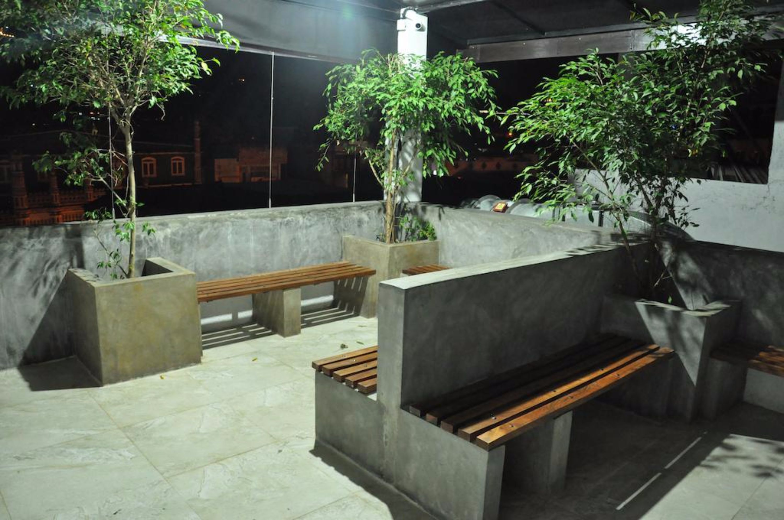 An outdoor seating area with concrete benches and planters with trees.