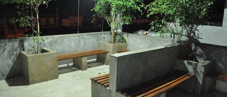 Zona exterior con bancos de hormigón y jardineras con árboles.