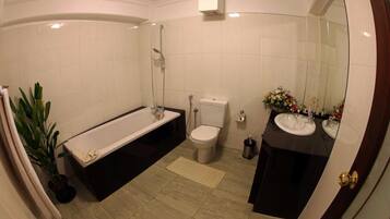 A bathroom with a bathtub, toilet, and two sinks.