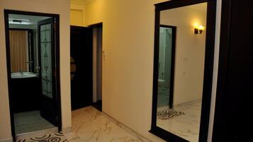 A hallway with a marble floor, a large mirror, and a door leading to a bathroom.