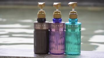Tres botellas de productos corporales LIGZY sobre un repisa.