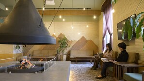 Un área de descanso moderna con una chimenea central, asientos y una gran pantalla de televisión en la pared.