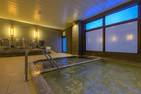 A spa area with a hot tub, wooden walls, and large windows.