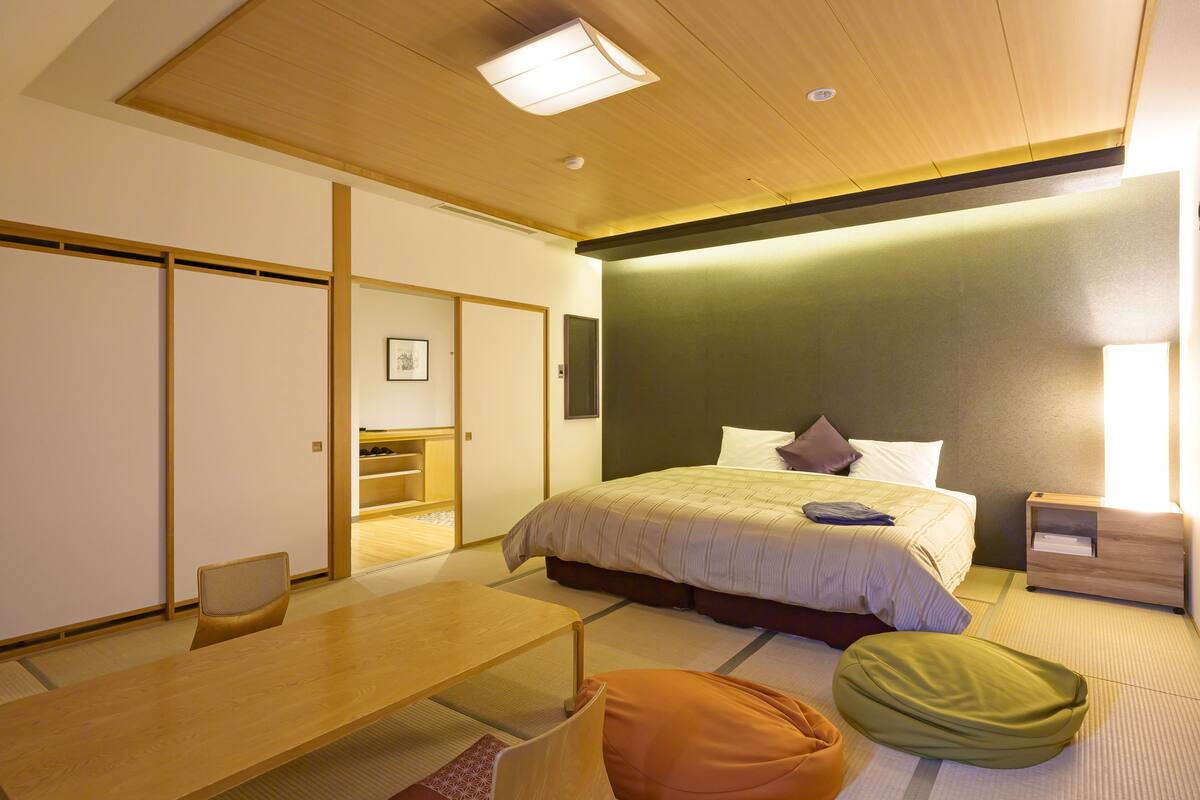 Hotellihuone, jossa on sänky, työpöytä, tuoli ja futon-patja.
