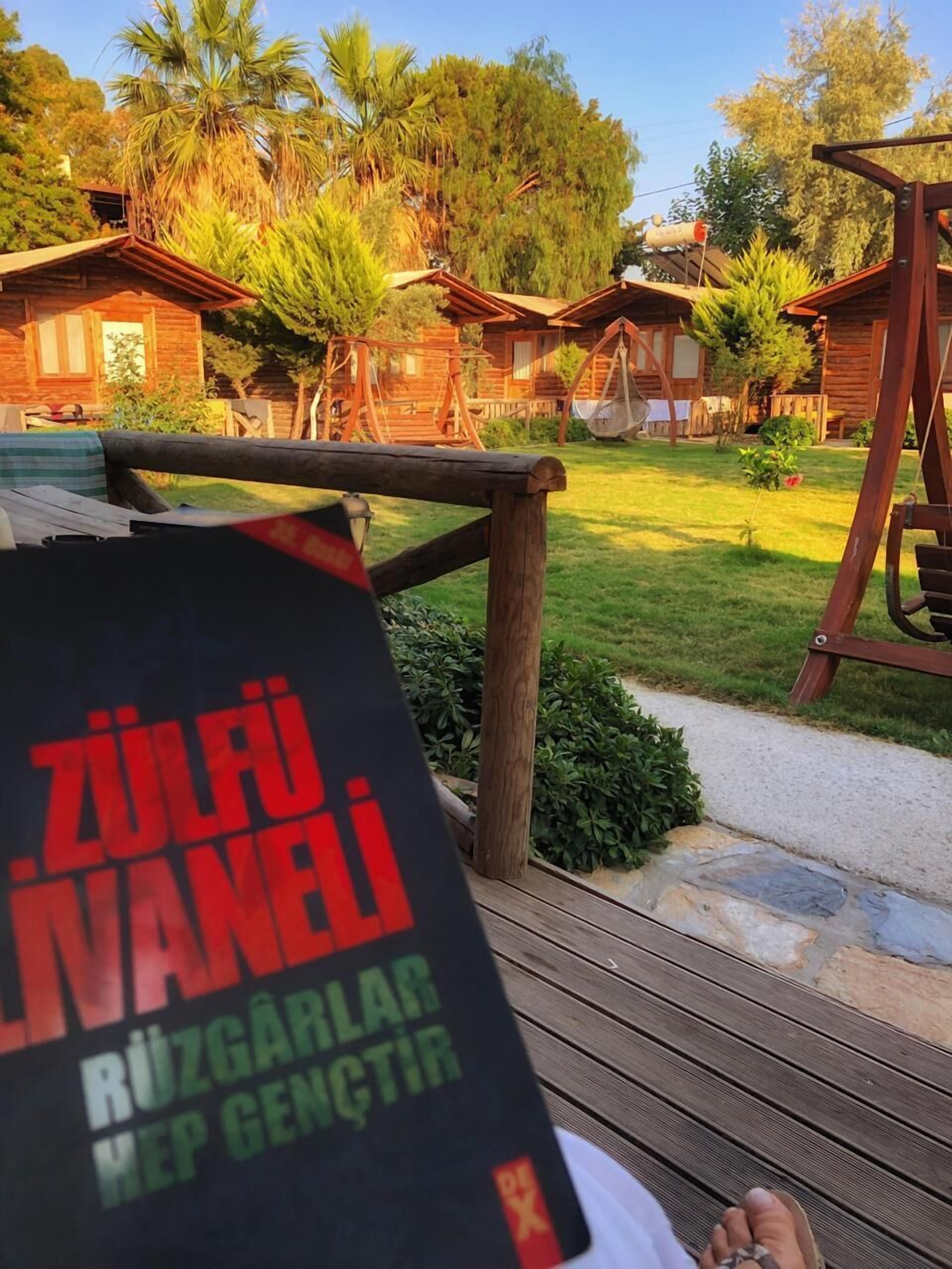 Una terraza de madera con un libro que dice "ZÜLÜM NANI" y "RÜZGÄRLICH HEP GENÇTİR".