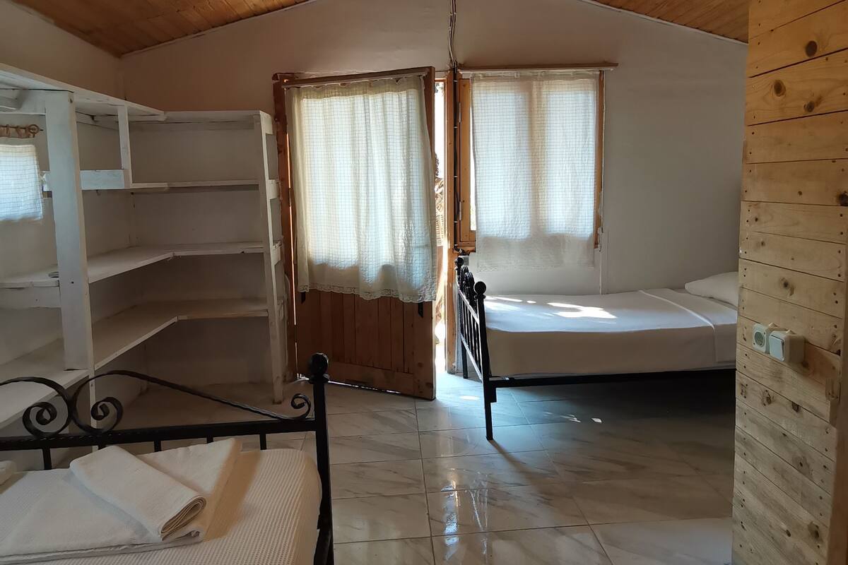 A room with wooden walls and ceiling, a bed, a bench, and a hanging light fixture.