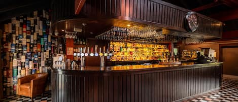 A bar with a checkered floor, wooden bar counter, and a wall of liquor bottles.