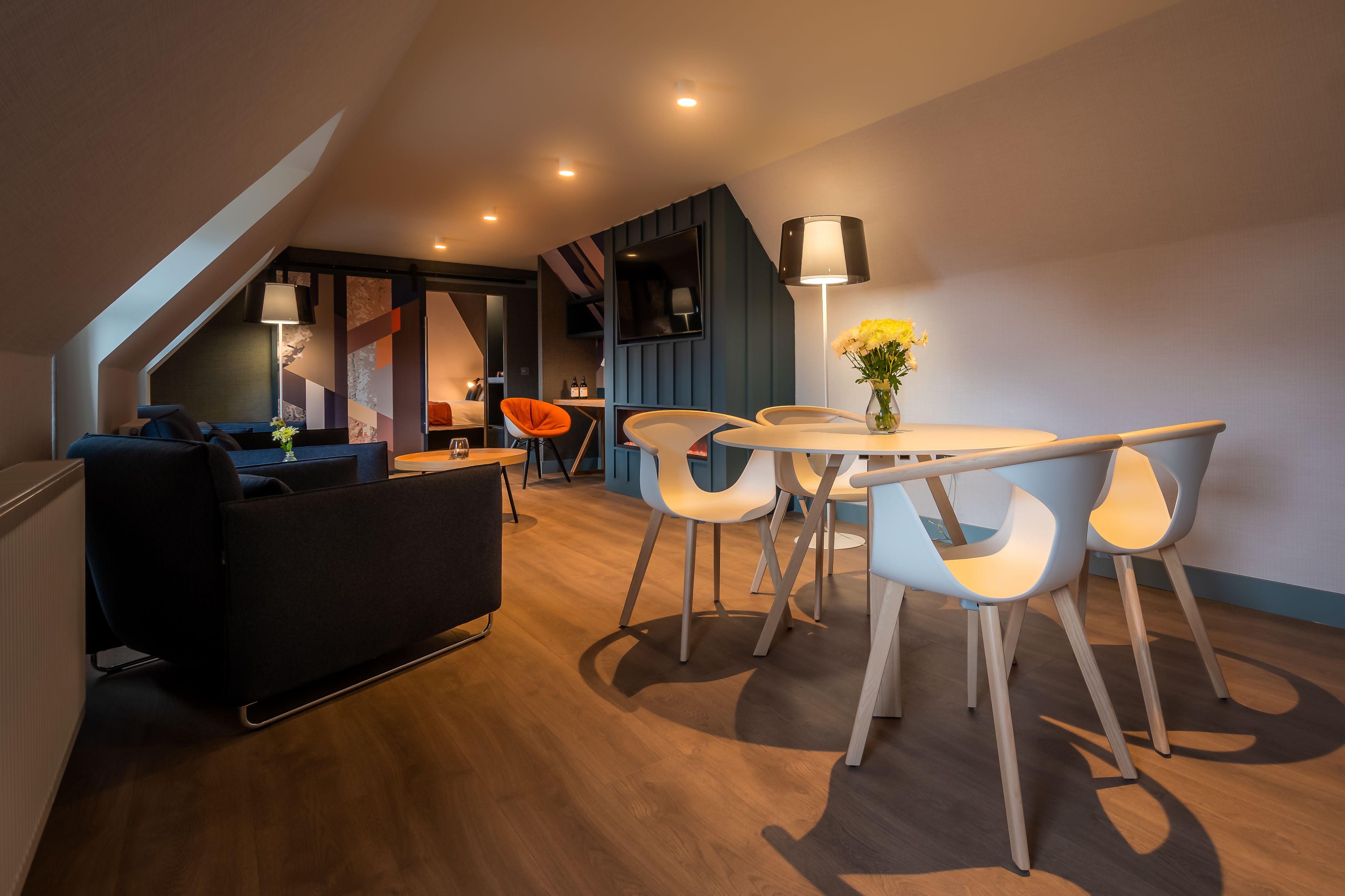 Uma sala de estar moderna com um sofá, uma mesa de jantar com cadeiras e uma televisão.