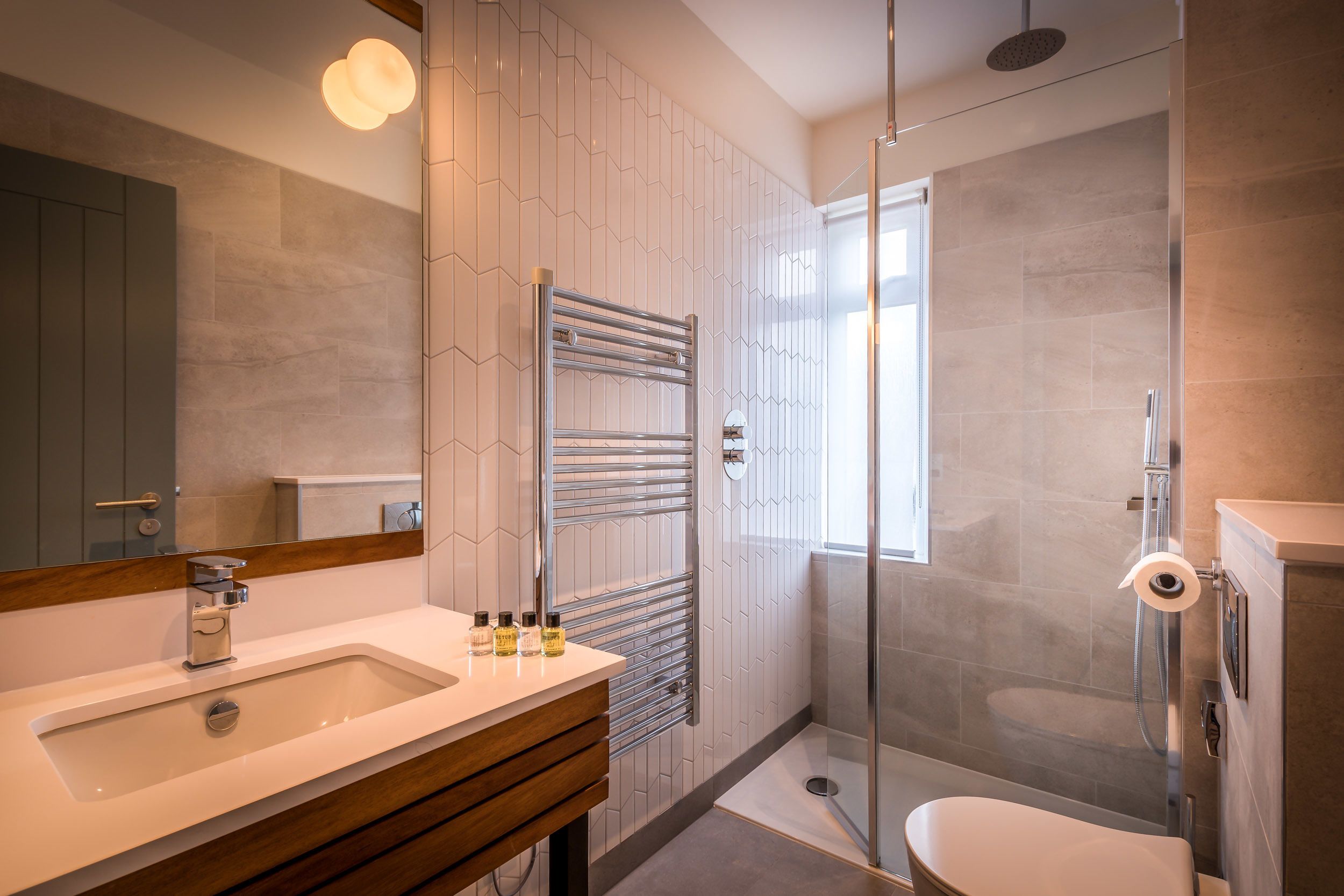A modern bathroom with a large mirror, a sink with a wooden vanity, a glass shower enclosure, and a toilet.