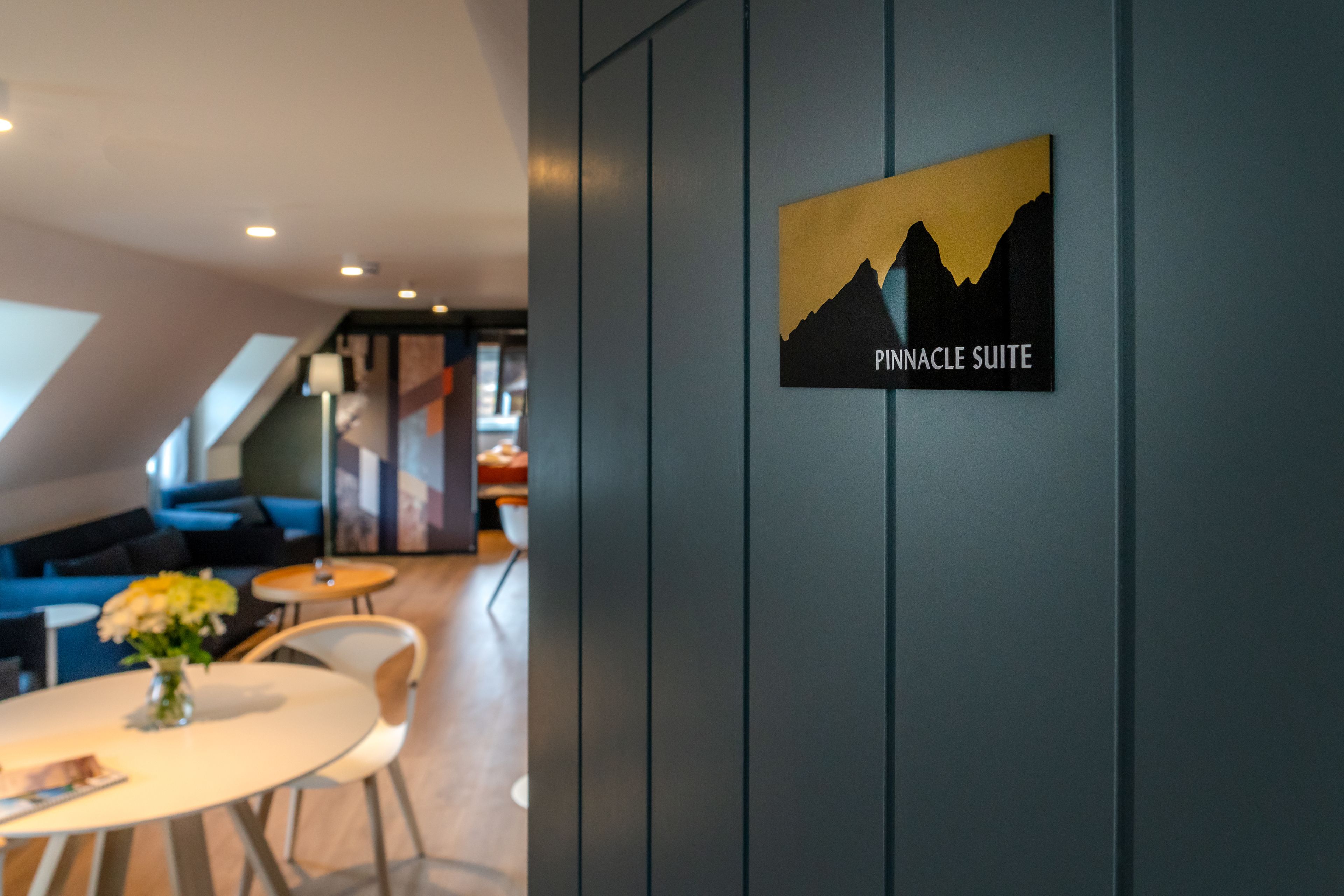 A Pinnacle Suite sign in a modern hotel lobby with a dining area and seating.