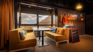 Un ambiente accogliente con soffitto in legno, un tavolo, due divani e vista su una montagna, oltre a un menu scritto su una lavagna.
