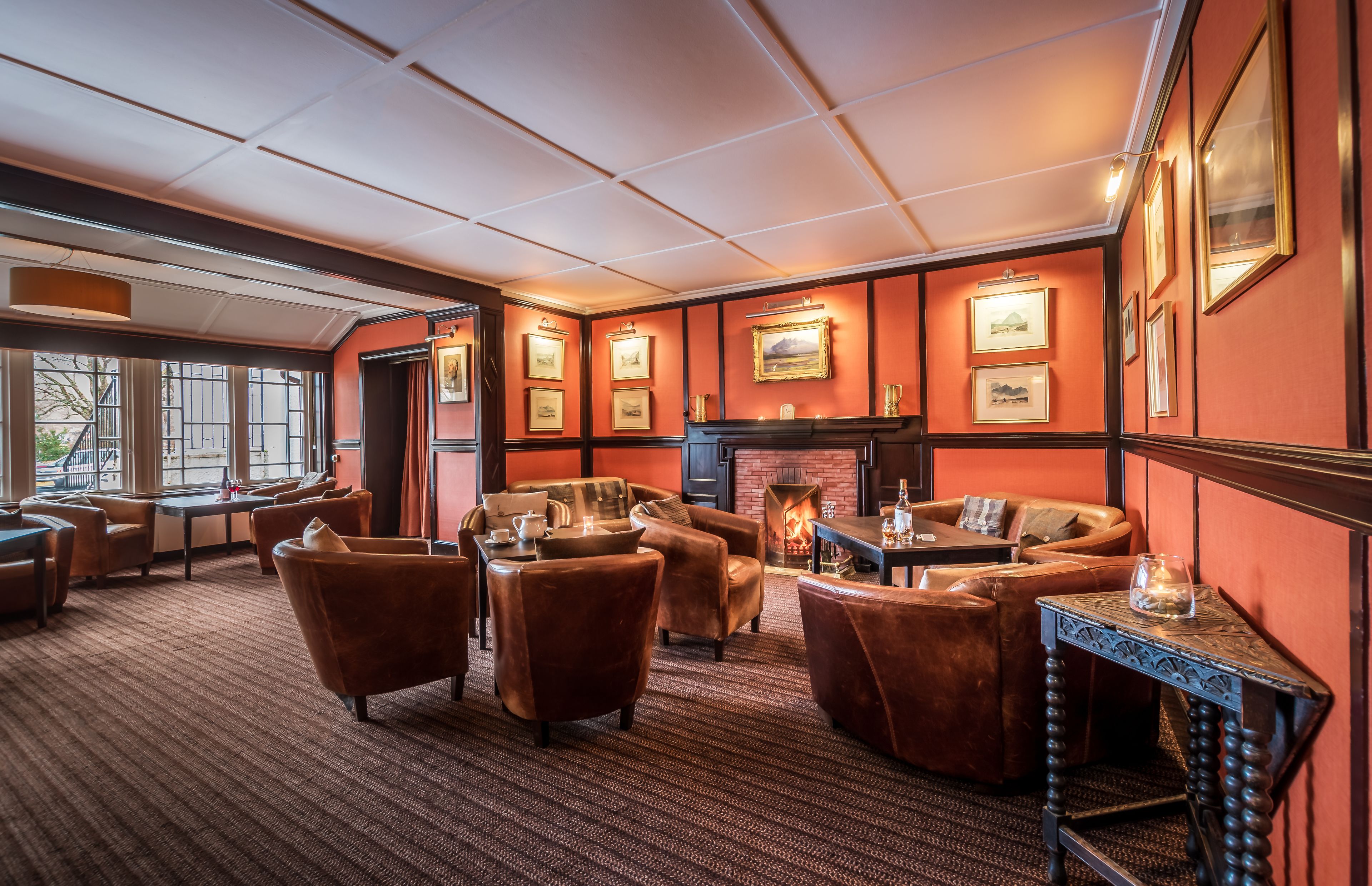 A cozy lounge area with leather sofas, a fireplace, and framed artwork on the walls.