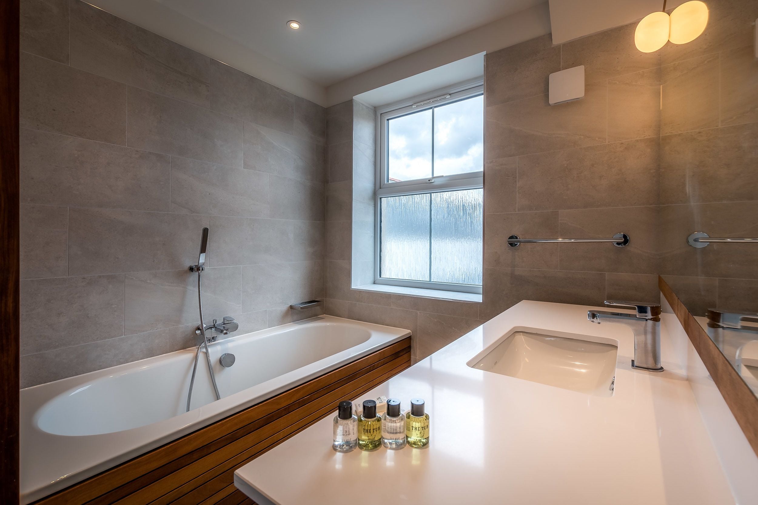 Ein modernes Badezimmer mit einer Badewanne, einem Waschbecken und einem Fenster.