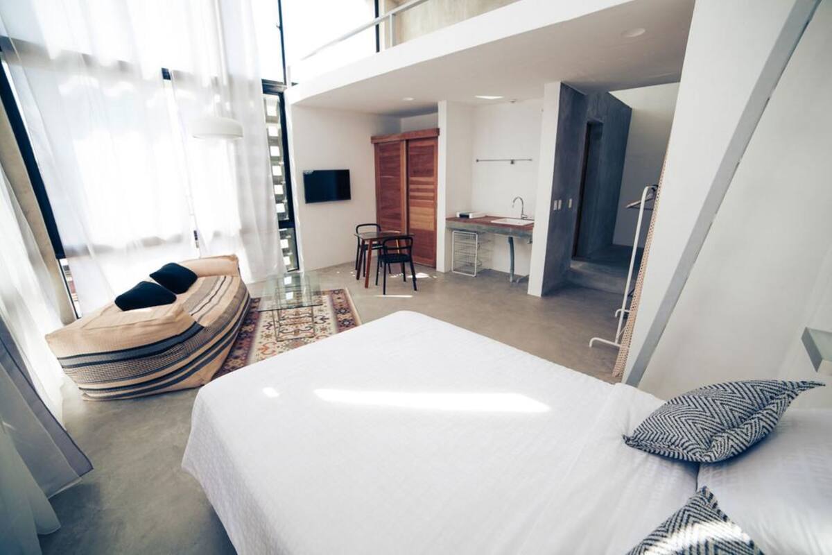 Une chambre d’hôtel moderne dotée d’un grand lit, d’un petit bureau, d’un coin salon et offrant une vue sur la ville.