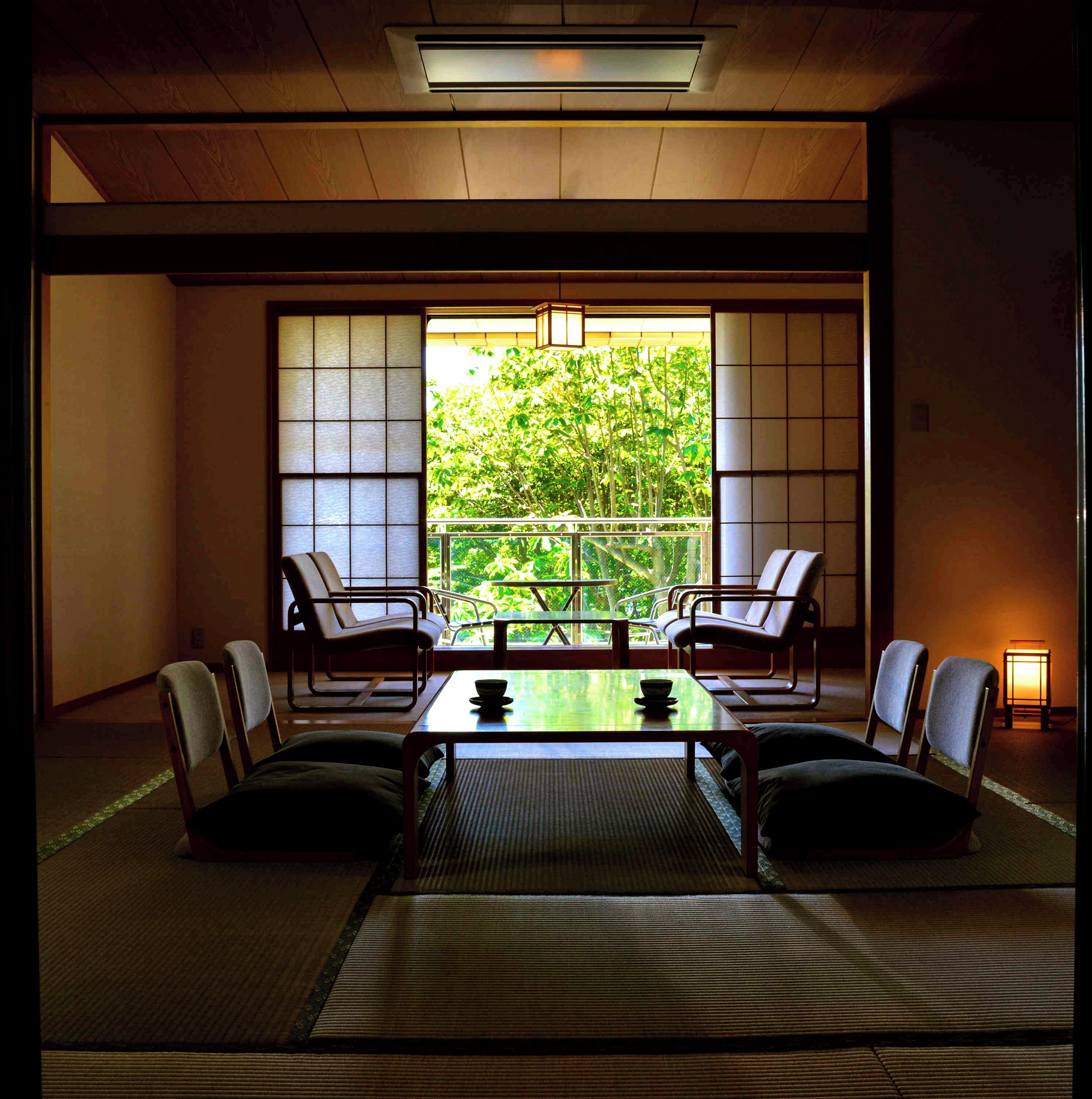 Um quarto japonês tradicional com tatames, uma mesa baixa e cadeiras.